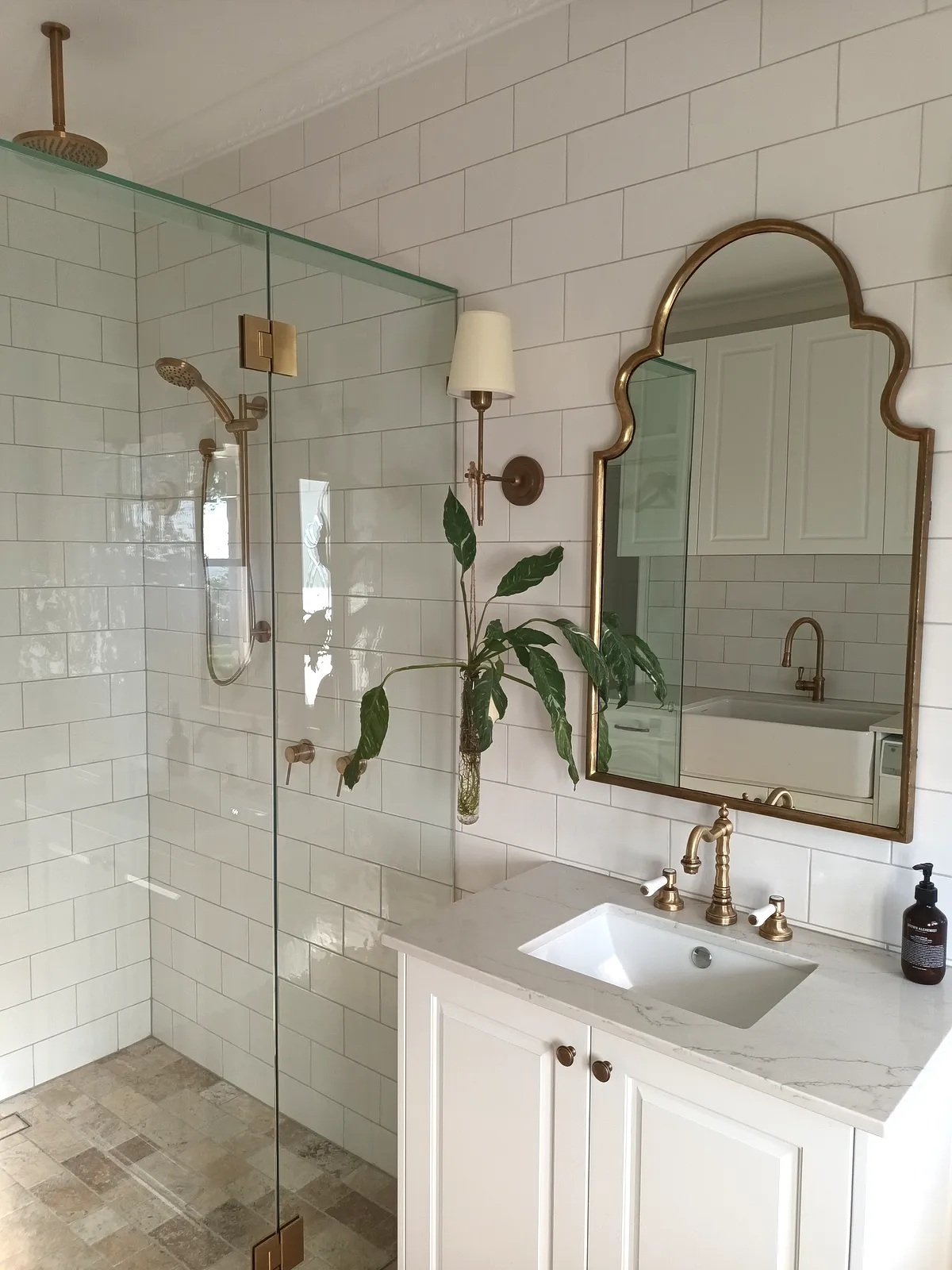 Heritage-style bathroom with brass fittings, an arched gold mirror, subway wall tiles and terracotta floor tiles, tiled by QLD World Tiles