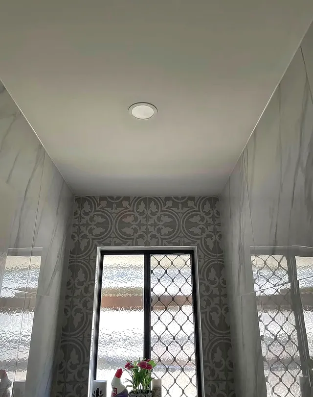 Small room with patterned grey floor tiles and marble-look wall tiles