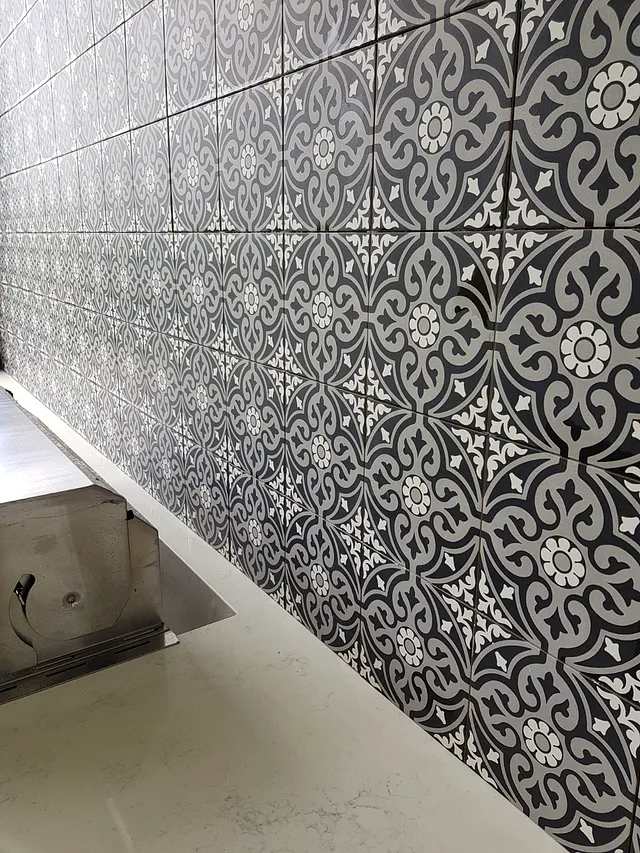 Close-up of black-and-white patterned wall tiles above an outdoor bench