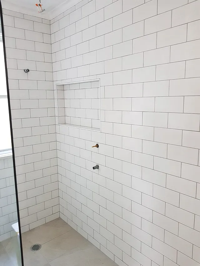 Walk-in shower with white subway tiles and a recessed niche