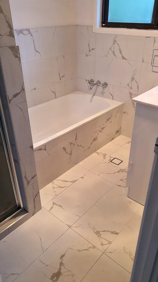 Built-in bath with marble-look tiled surround and walls