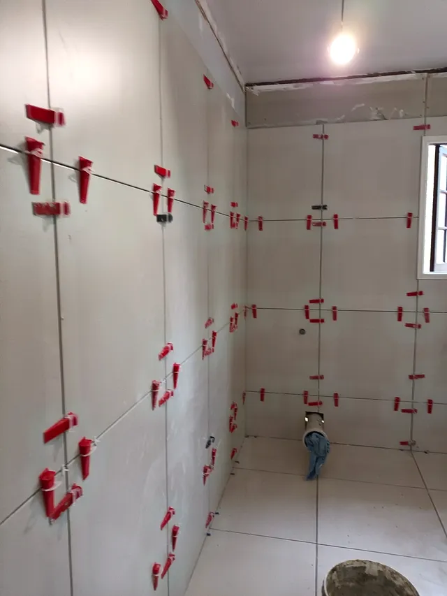 Bathroom wall tiles being installed with levelling clips for a flat finish