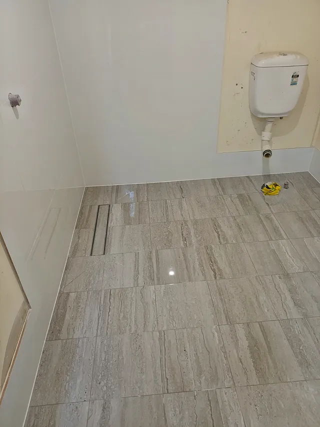Room with striped wood-look floor tiles, a linear drain and white wall tiles