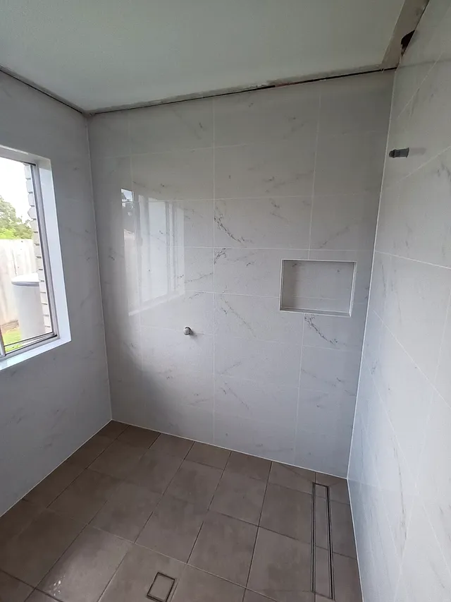 Bathroom with marble-look walls, a window and a recessed shelf niche
