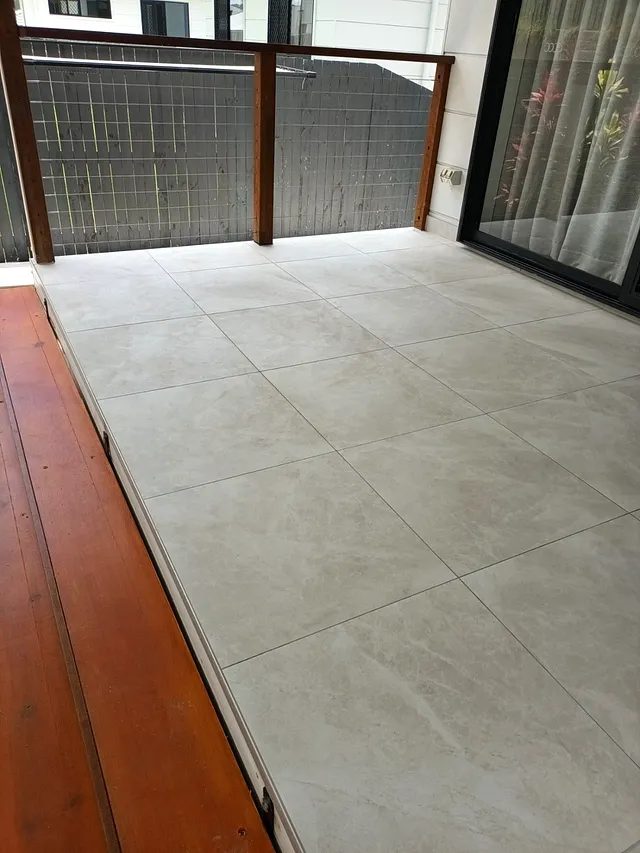 Large-format outdoor tiles beside a timber deck under cover