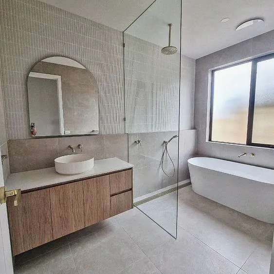 Bathroom with a floating timber vanity, round basin, freestanding bath and glass shower