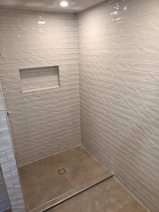 Shower with textured wave-pattern wall tiles, a niche and linear drain