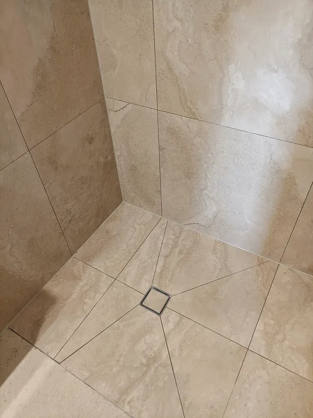 Shower floor tiled with tiles cut on the diagonal towards a square drain