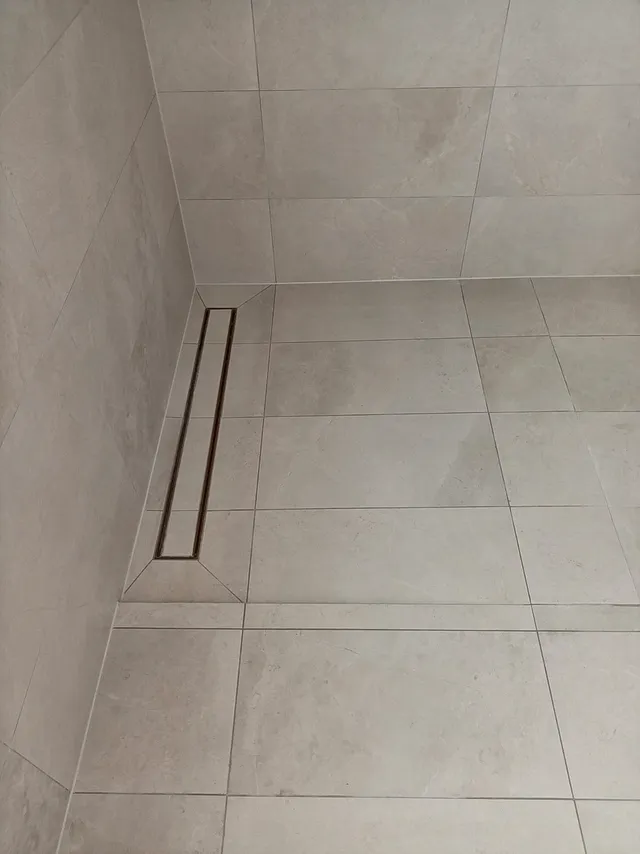 Shower floor with a long linear drain and large-format tiles