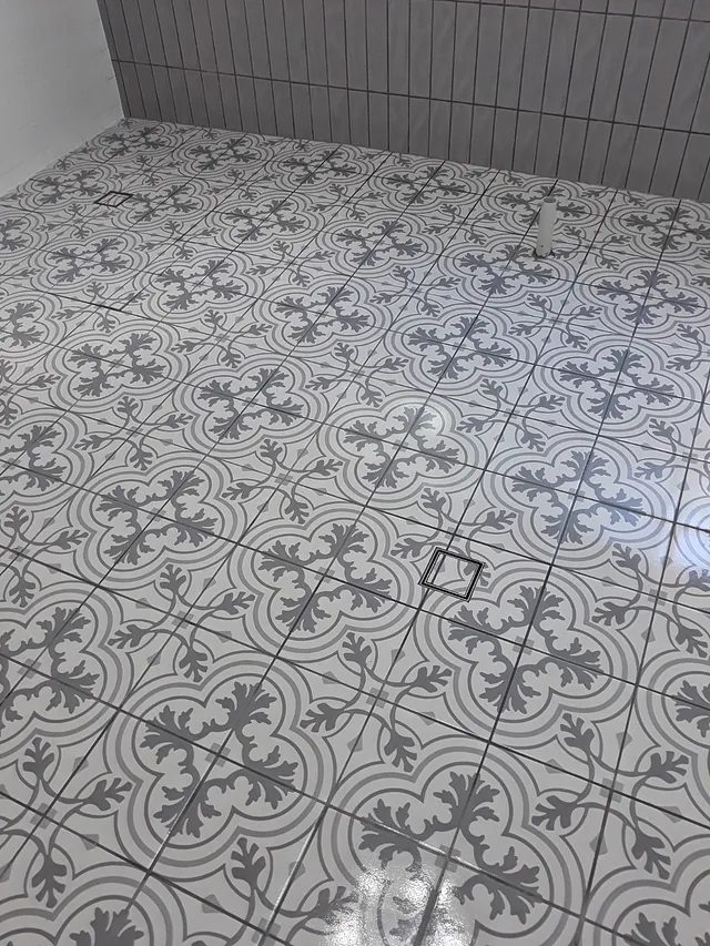 Close-up of grey and white patterned floor tiles with a square floor waste