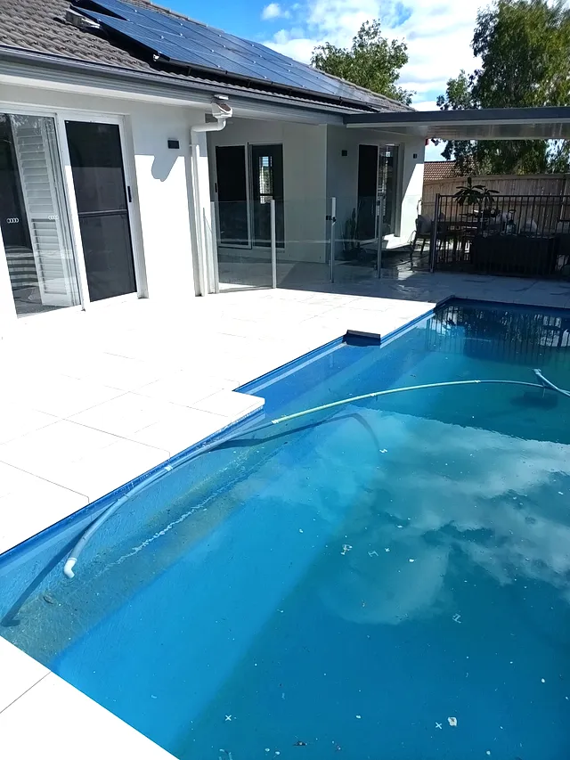Pool with a light tiled surround on a sunny day