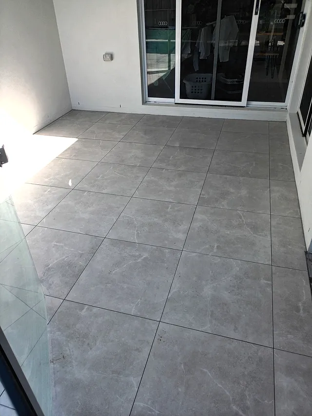 Patio tiled with large-format grey tiles with glass fencing