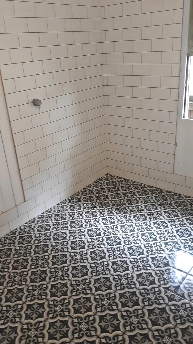 White subway-tile shower with a black-and-white patterned floor