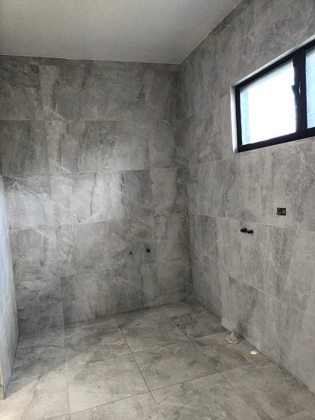 Bathroom with grey large-format wall and floor tiles and a window