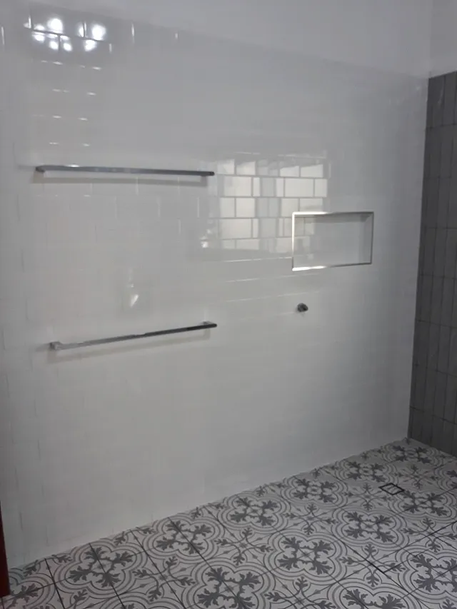 Bathroom with white gloss wall tiles, towel rails, a niche and a patterned floor