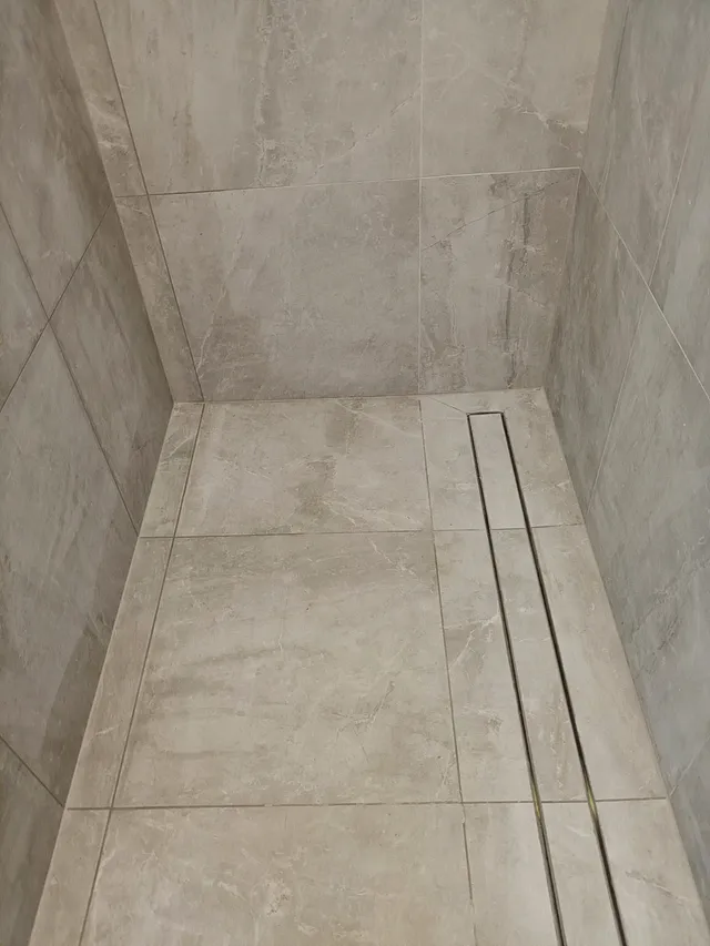 Shower with large-format stone-look tiles and a linear drain