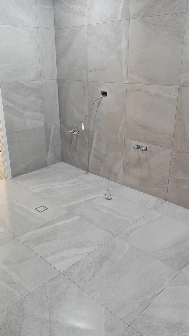 Shower recess with large-format grey tiles and a floor drain