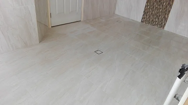 Large-format floor tiles with a floor waste and a mosaic feature strip