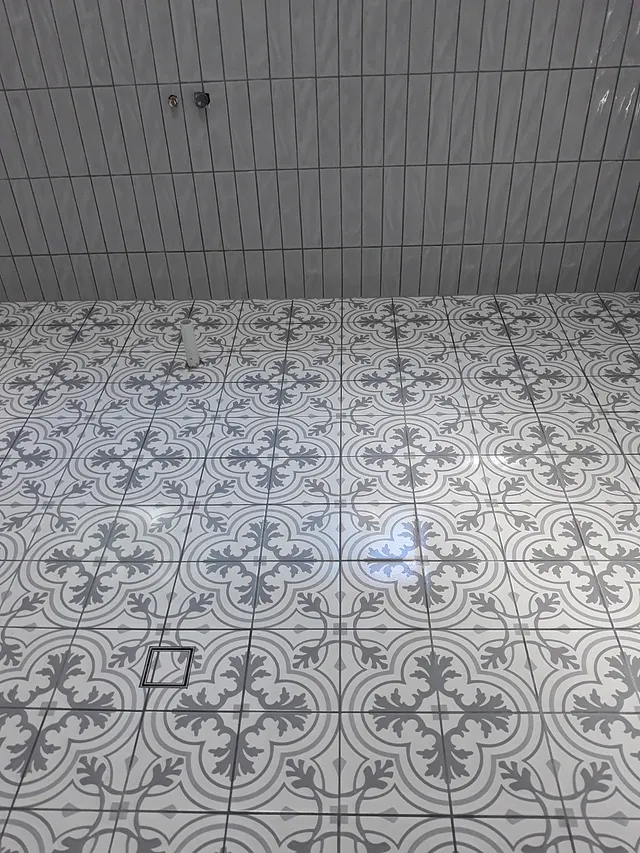 Grey and white patterned floor tiles with vertical stacked wall tiles above